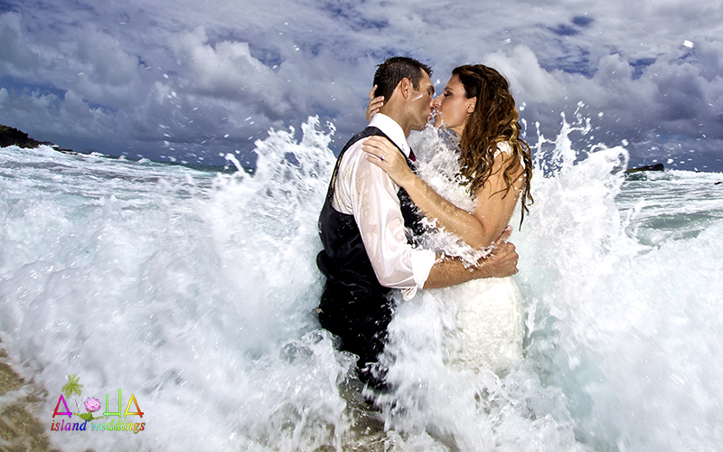 a kiss in the pacific ocean as the wave of love crashes over the newly weds